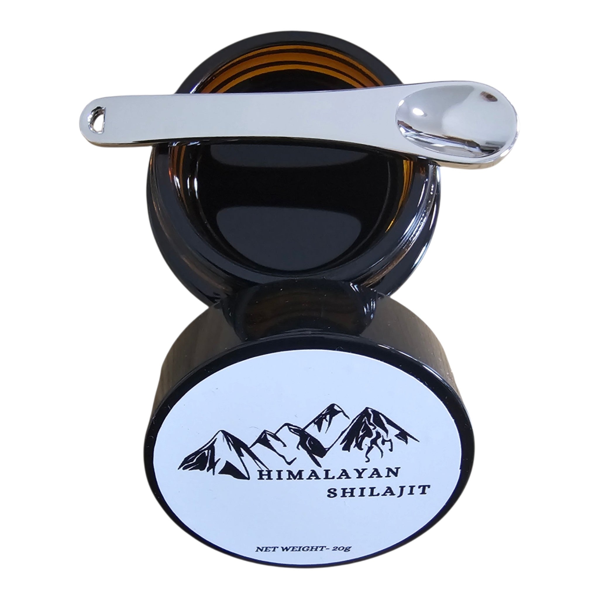 An open round black jar of Himalayan Shilajit with a silver metal scoop resting across the top, shown against a plain white background. The bottom of the jar features a white label with a black mountain graphic and the text 'HIMALAYAN SHILAJIT'.